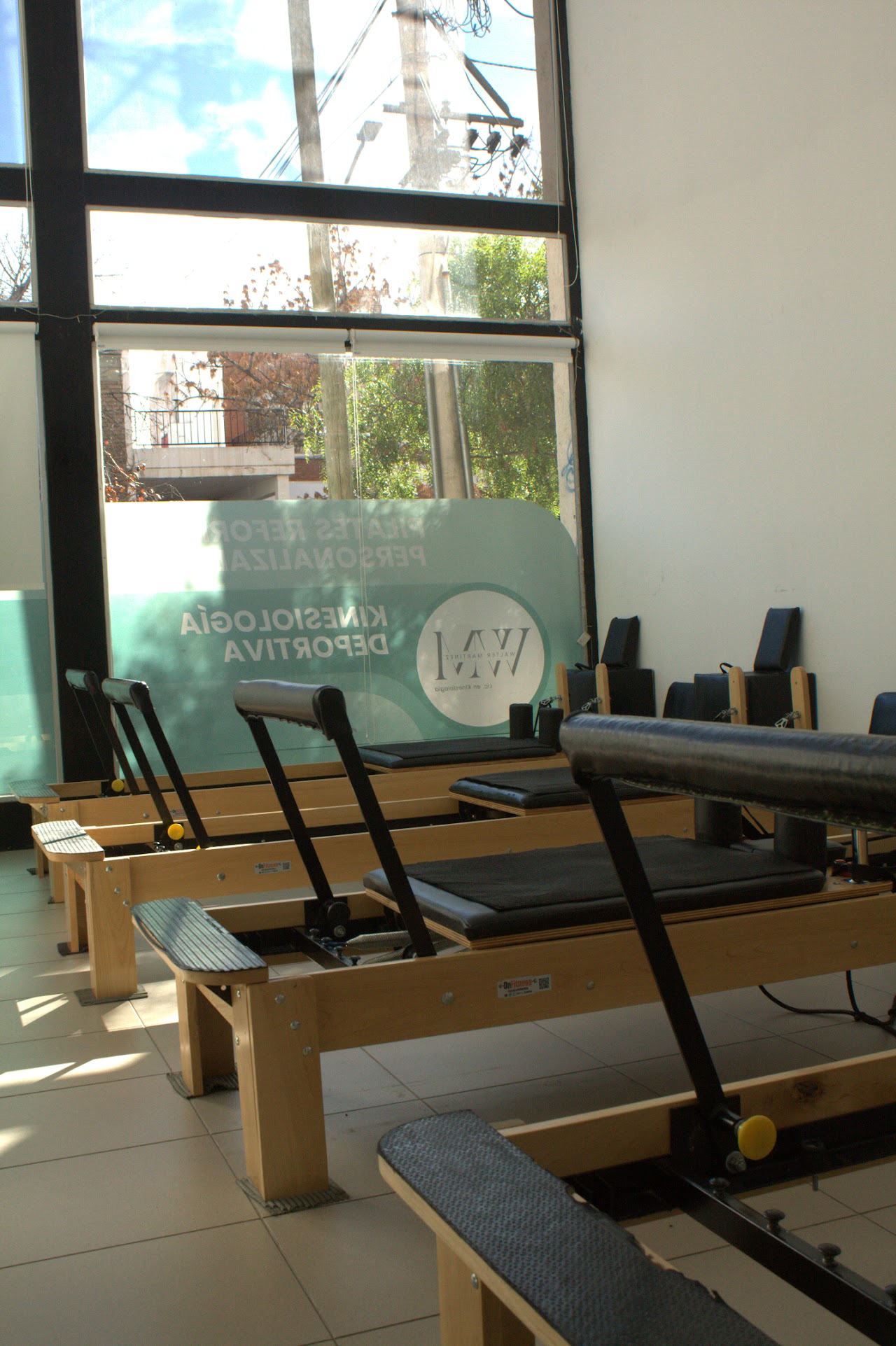 Bright and clean private physiotherapy consultation room with modern treatment bed, posture grid wall chart, professional kinesiology assessment equipment, soft warm natural sunlight, wooden floor, tranquil medical atmosphere.